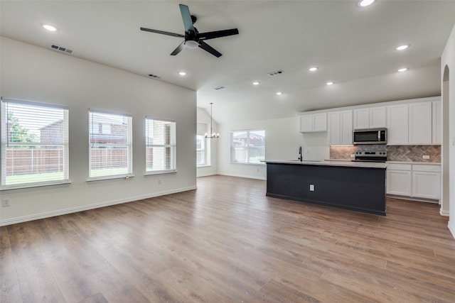 kitchen with stainless steel appliances, a center island with sink, white cabinets, sink, and light wood-type flooring