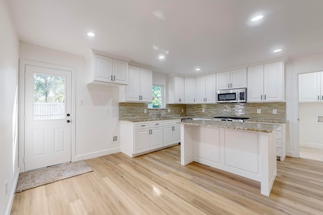 kitchen with light hardwood / wood-style floors, a healthy amount of sunlight, and white cabinetry