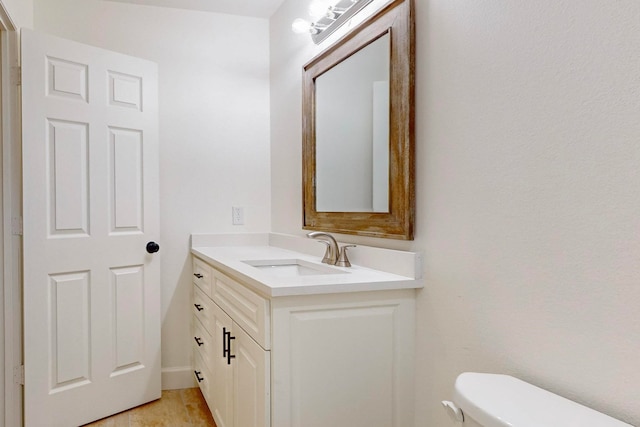 bathroom with wood-type flooring, vanity, and toilet