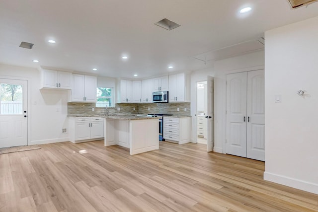 kitchen featuring stainless steel appliances, white cabinets, light hardwood / wood-style flooring, and a wealth of natural light