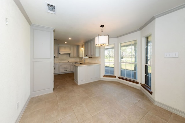 kitchen with light tile patterned floors, ornamental molding, sink, tasteful backsplash, and decorative light fixtures