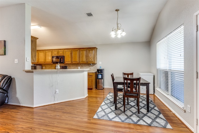 kitchen with kitchen peninsula, hanging light fixtures, a chandelier, and light wood-type flooring