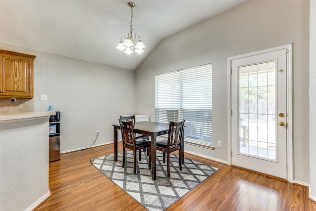 dining space featuring lofted ceiling, a chandelier, and light hardwood / wood-style floors