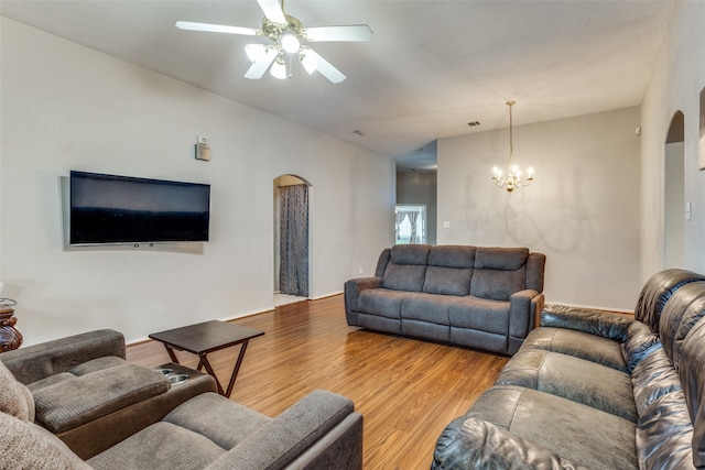 living room with ceiling fan with notable chandelier and light hardwood / wood-style flooring