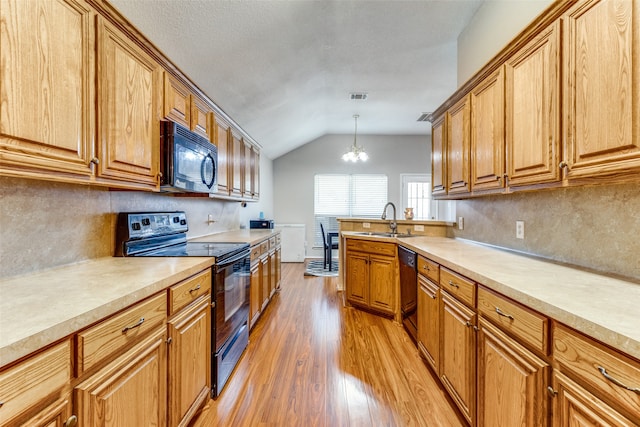 kitchen with pendant lighting, light hardwood / wood-style flooring, vaulted ceiling, a notable chandelier, and black appliances