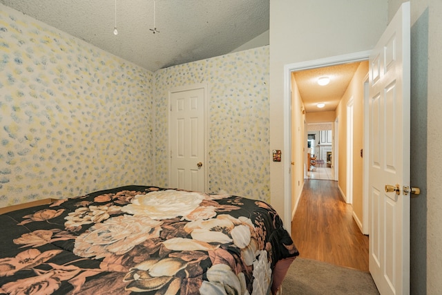 bedroom featuring wood-type flooring, a textured ceiling, and lofted ceiling