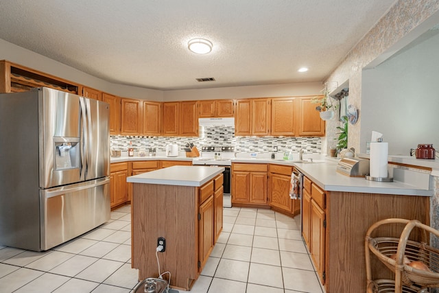 kitchen featuring stainless steel appliances, a kitchen island, light tile patterned floors, and a textured ceiling