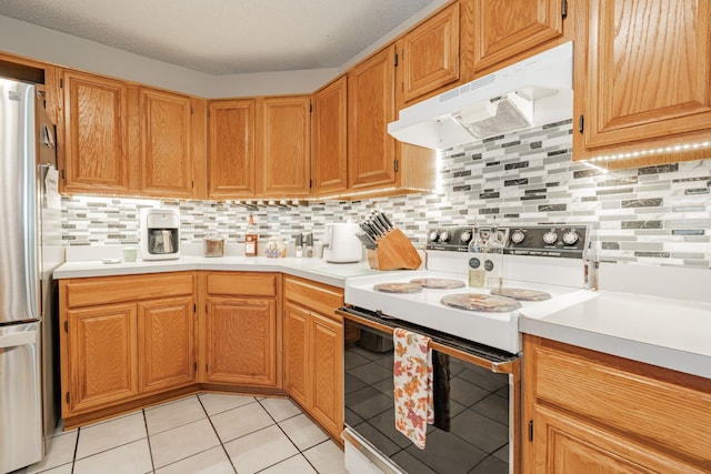 kitchen featuring light tile patterned flooring, electric range, stainless steel refrigerator, and backsplash