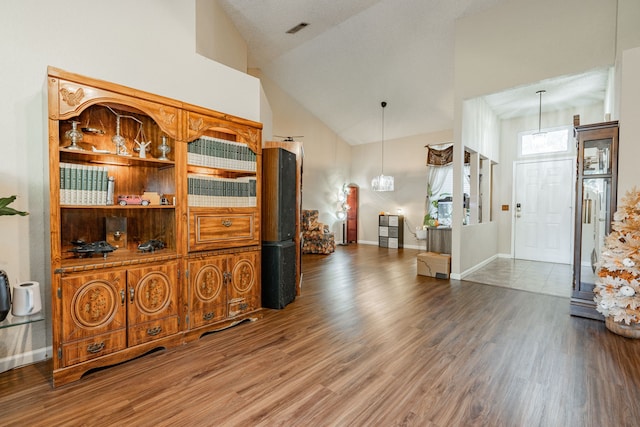 foyer with wood-type flooring and high vaulted ceiling