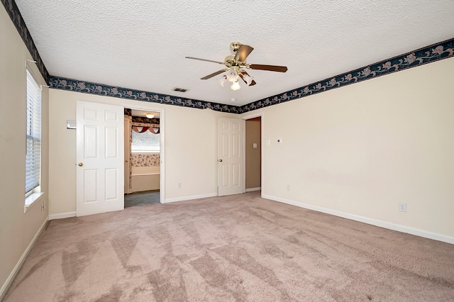 unfurnished bedroom featuring a textured ceiling, ceiling fan, light carpet, and connected bathroom