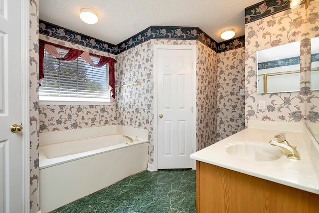 bathroom with a washtub, a textured ceiling, and vanity