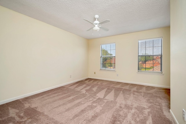 spare room with a textured ceiling, ceiling fan, and light colored carpet