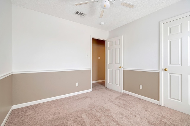 carpeted empty room with ceiling fan and a textured ceiling