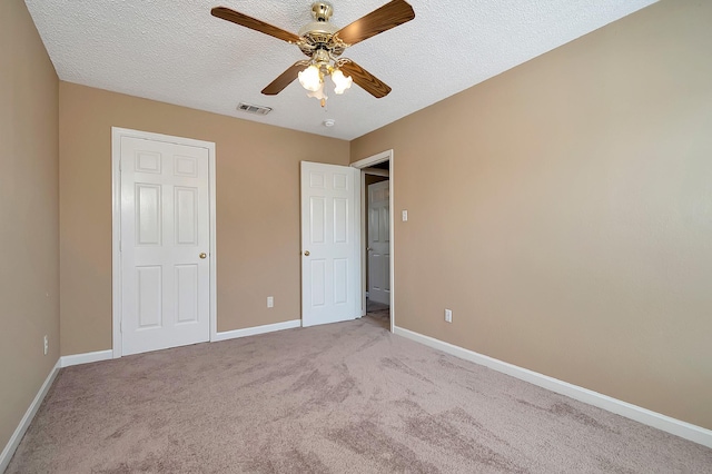 unfurnished bedroom featuring light carpet, ceiling fan, and a textured ceiling