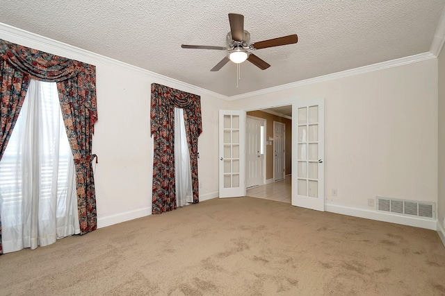 carpeted empty room featuring a textured ceiling, ceiling fan, ornamental molding, and french doors