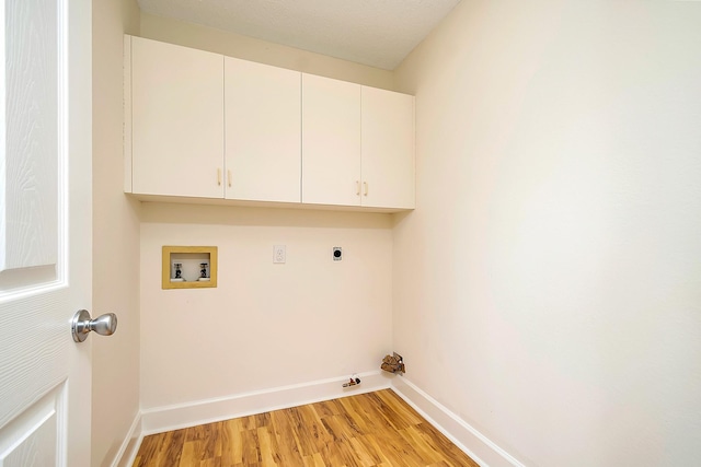 clothes washing area featuring cabinets, electric dryer hookup, gas dryer hookup, hookup for a washing machine, and light hardwood / wood-style flooring