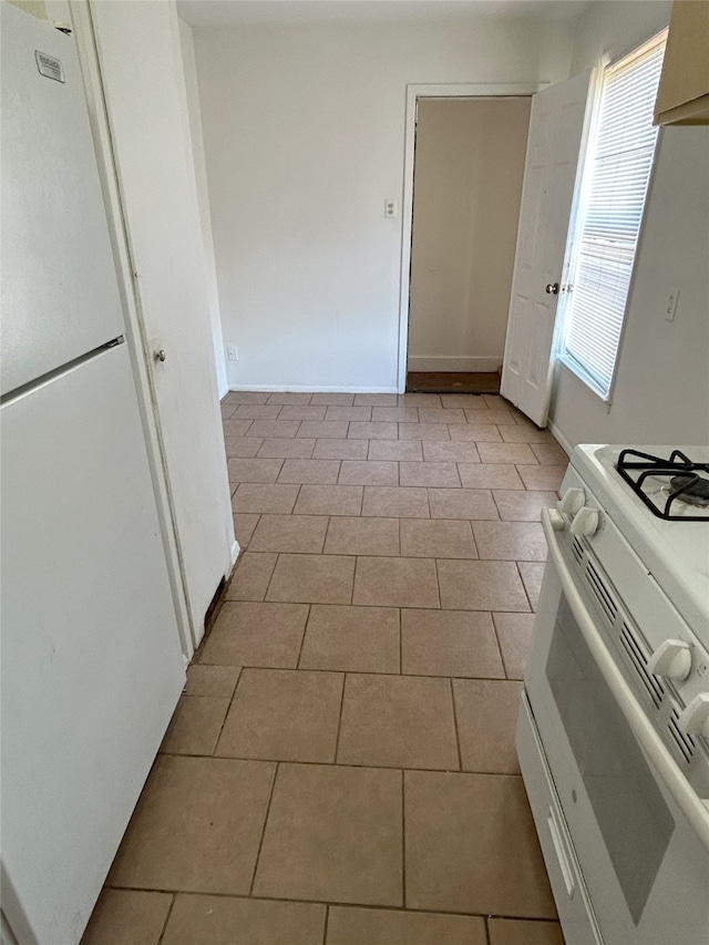 kitchen featuring light tile patterned flooring, white appliances, white cabinetry, and extractor fan