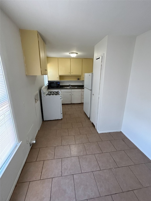 kitchen with light tile patterned flooring, white appliances, and sink