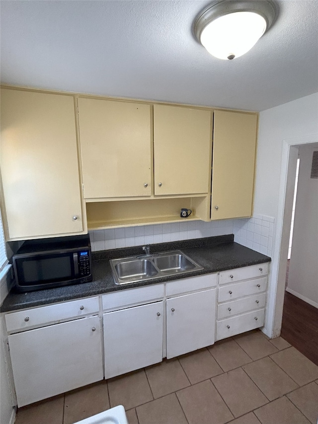 kitchen with a textured ceiling, sink, light tile patterned floors, and backsplash