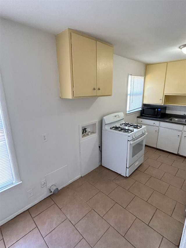 kitchen with sink, light tile patterned floors, and white range with gas cooktop