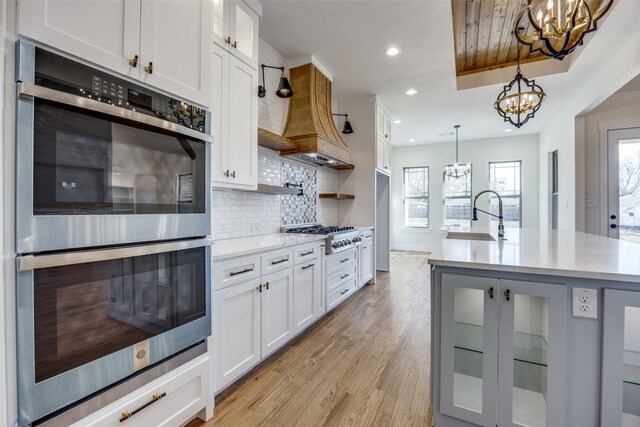 kitchen featuring sink, tasteful backsplash, decorative light fixtures, white cabinets, and appliances with stainless steel finishes