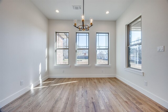 unfurnished room featuring light hardwood / wood-style flooring and an inviting chandelier