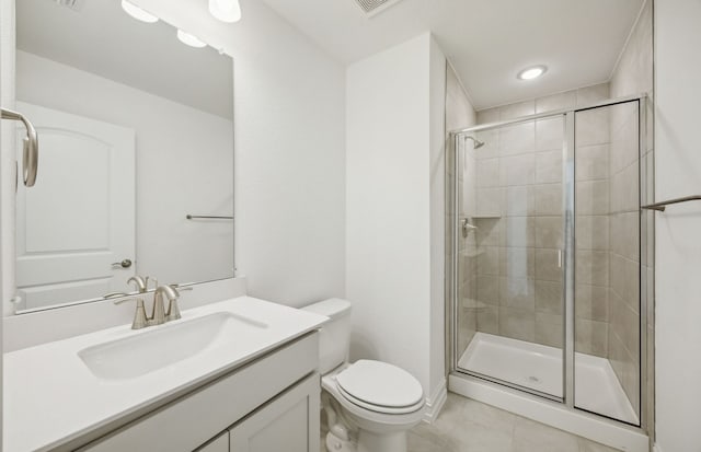 bathroom featuring tile patterned floors, vanity, a shower with shower door, and toilet