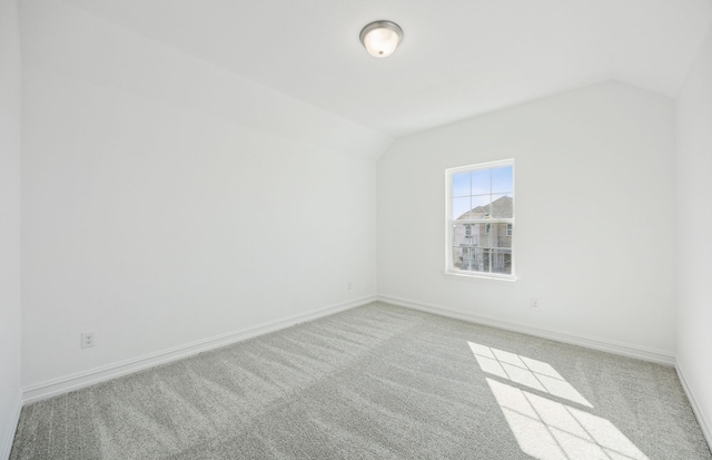 carpeted empty room with vaulted ceiling