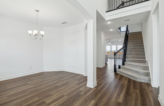 interior space featuring a towering ceiling, ceiling fan with notable chandelier, and dark wood-type flooring