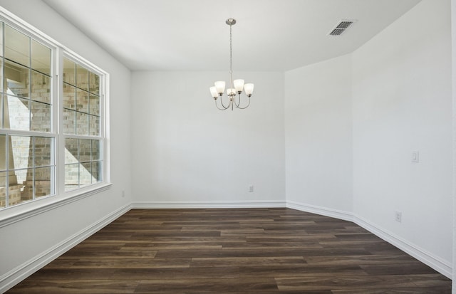 empty room with a chandelier, dark hardwood / wood-style flooring, and a healthy amount of sunlight