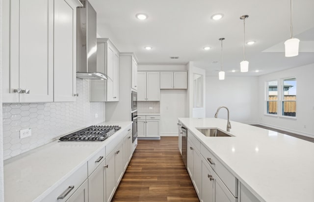 kitchen featuring stainless steel appliances, dark wood-type flooring, sink, wall chimney range hood, and pendant lighting