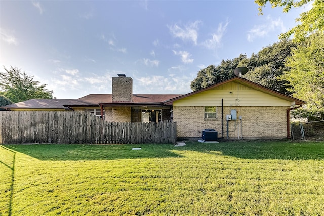 rear view of property with a lawn and central AC