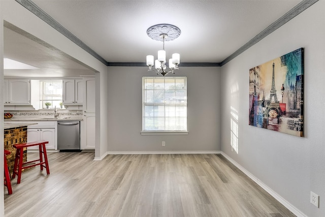 dining area featuring a healthy amount of sunlight, crown molding, sink, and an inviting chandelier