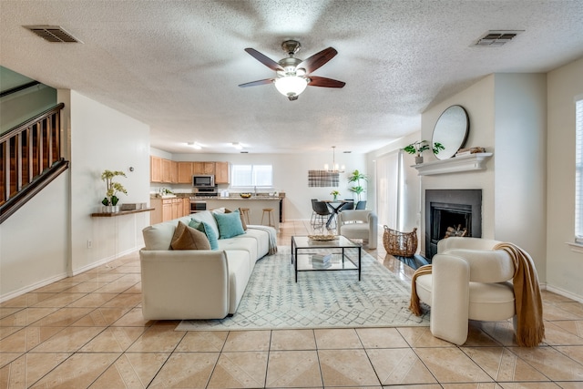 living room featuring ceiling fan, light tile patterned flooring, and a textured ceiling