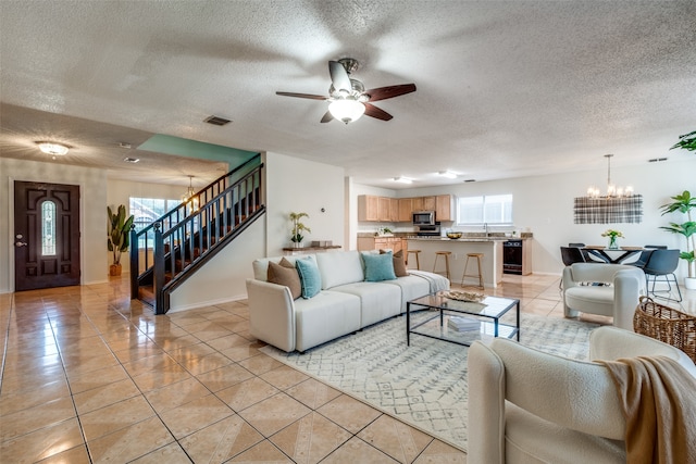 tiled living room with sink, ceiling fan with notable chandelier, and a textured ceiling