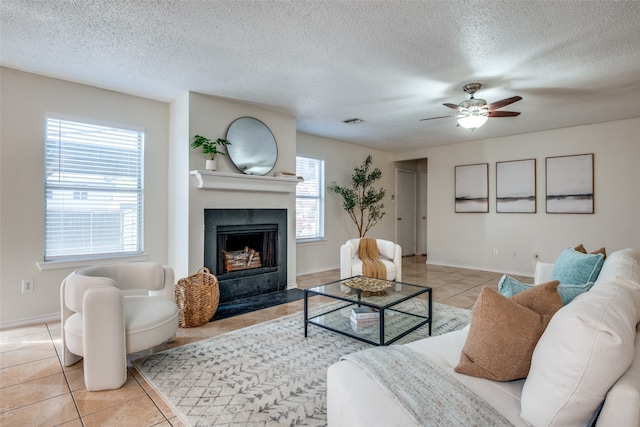 living room with ceiling fan, light tile patterned floors, and a textured ceiling