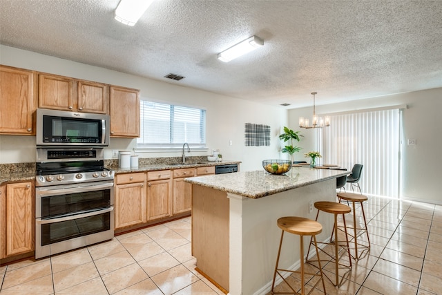 kitchen with a center island, light tile patterned floors, a textured ceiling, and appliances with stainless steel finishes