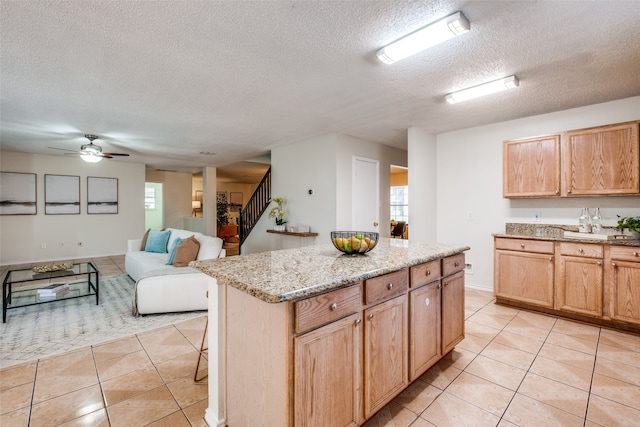 kitchen featuring a textured ceiling, a center island, light tile patterned floors, and a wealth of natural light