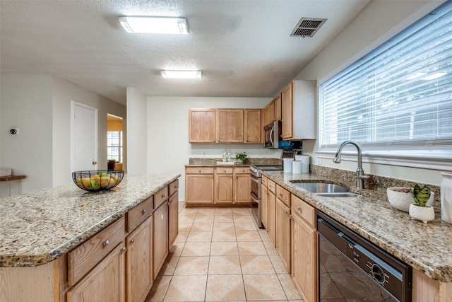 kitchen with sink, light stone counters, a textured ceiling, a kitchen island, and appliances with stainless steel finishes