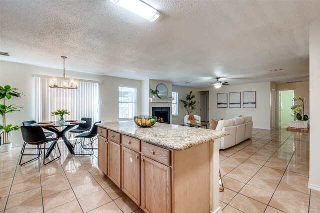 kitchen featuring pendant lighting, a kitchen island, light tile patterned floors, and a textured ceiling