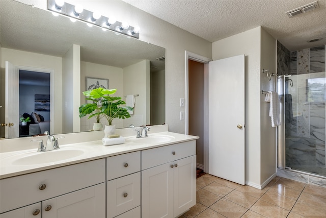 bathroom with tile patterned flooring, vanity, an enclosed shower, and a textured ceiling