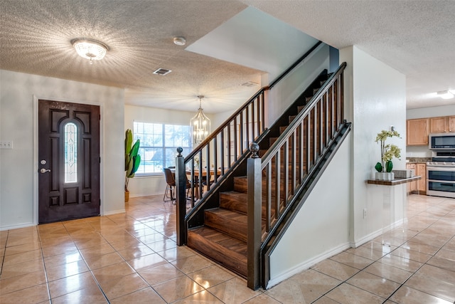 foyer with light tile patterned flooring, a textured ceiling, and an inviting chandelier