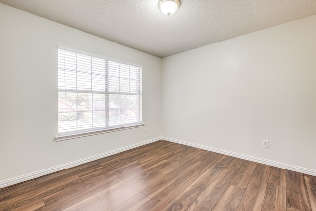 unfurnished room with a textured ceiling and dark hardwood / wood-style flooring