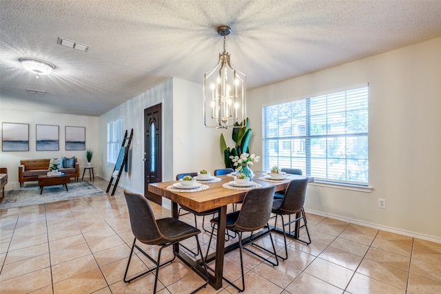 dining room featuring a notable chandelier, light tile patterned flooring, and a textured ceiling