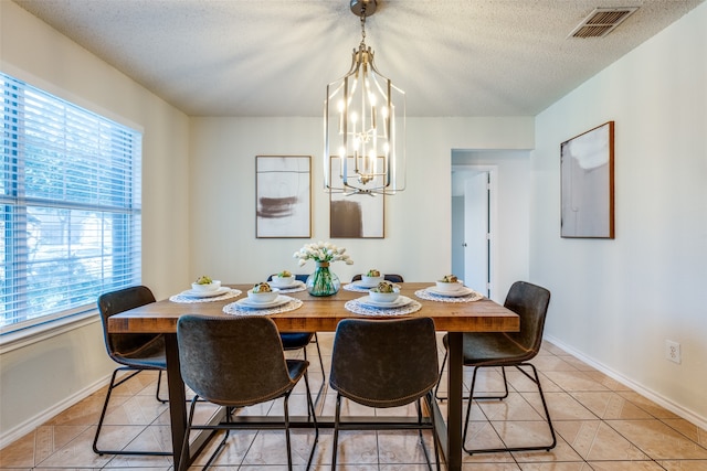 dining space with light tile patterned floors, a textured ceiling, and a notable chandelier