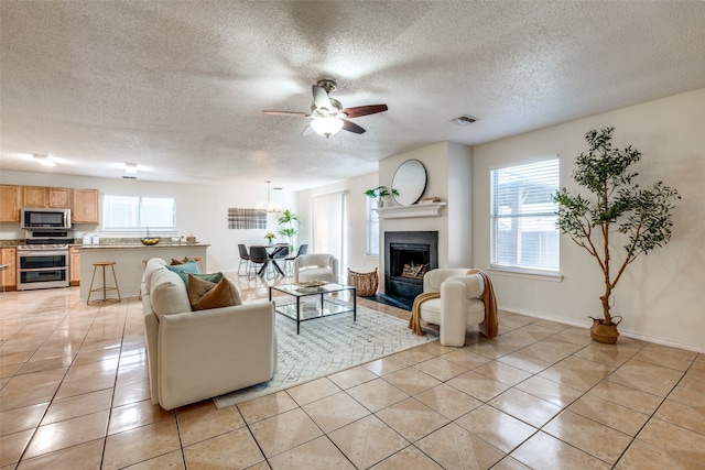 tiled living room featuring a textured ceiling, a wealth of natural light, and ceiling fan