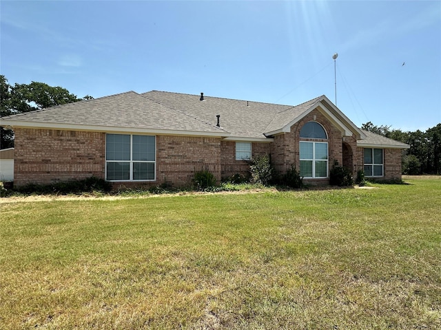 view of front facade featuring brick siding, a shingled roof, and a front yard