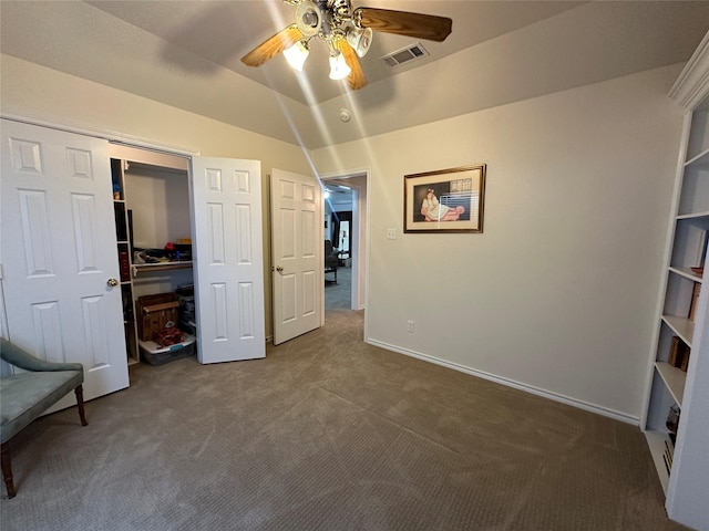 unfurnished bedroom with a closet, ceiling fan, visible vents, dark colored carpet, and baseboards
