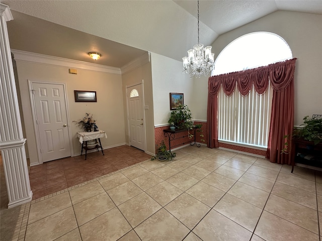 tiled entrance foyer featuring ornamental molding, vaulted ceiling, and an inviting chandelier