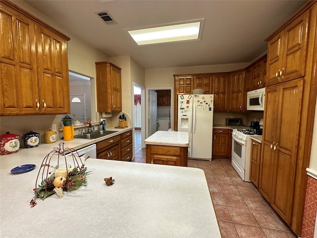 kitchen with washer / dryer, a center island, white appliances, sink, and kitchen peninsula